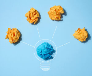 The concept of inspiration with new ideas, the search for creative solutions, crumpled sheets of paper in the form of balls on a blue background